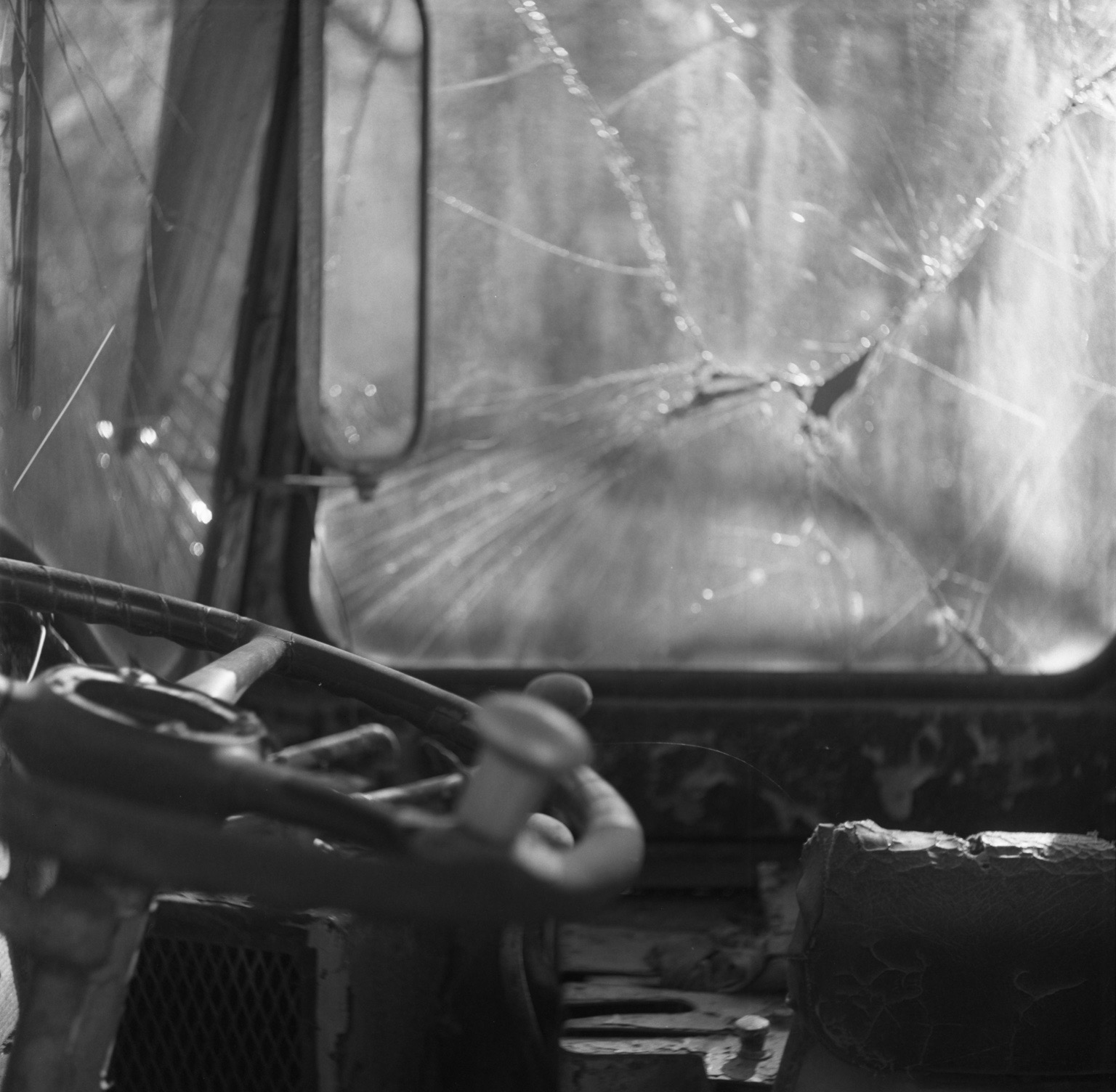 The interior of an abandoned vehicle seen through a shattered windshield