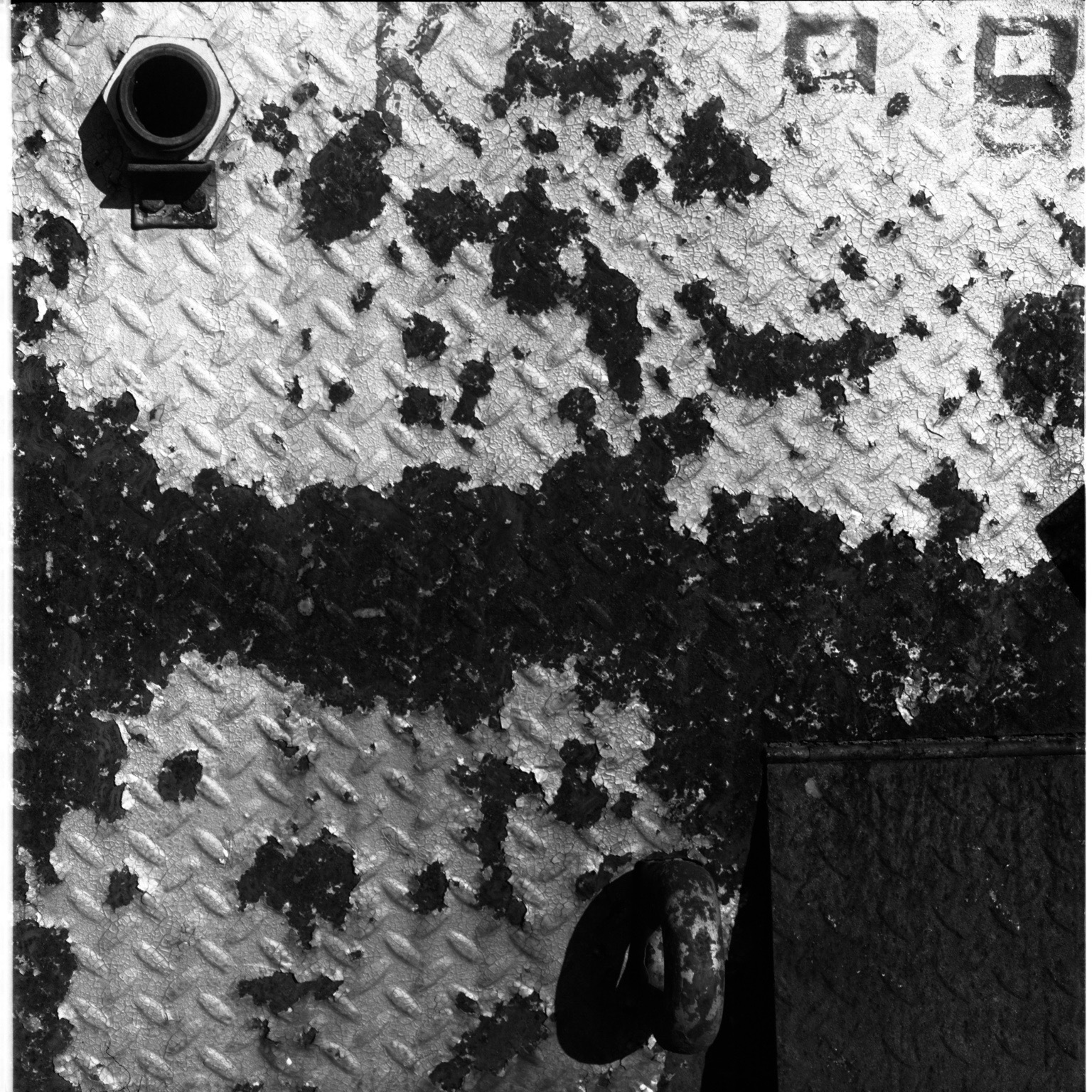 Peeling paint and hardware across a textured steel surface